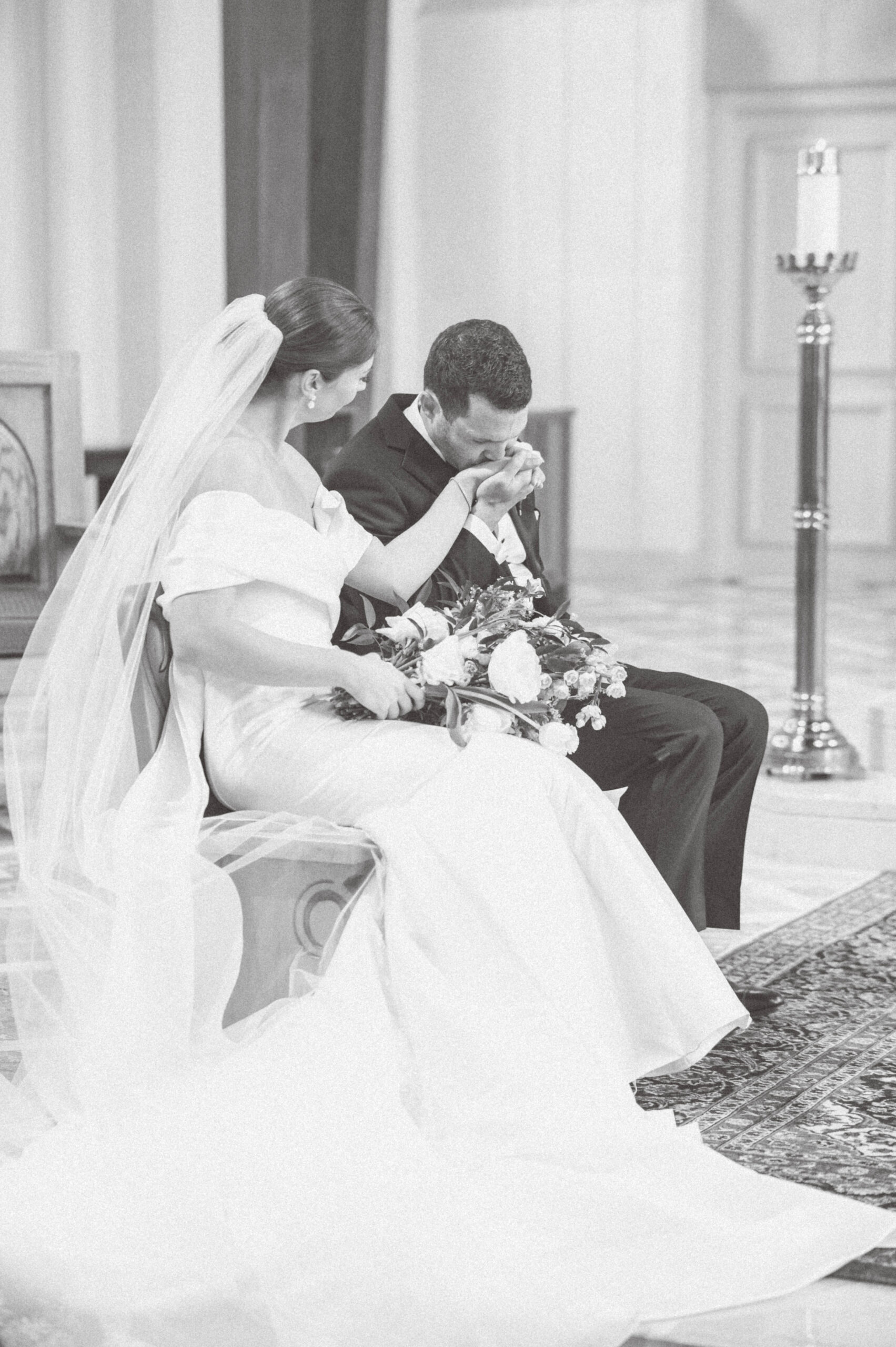 bride and groom sitting with groom kissing bride's hand
