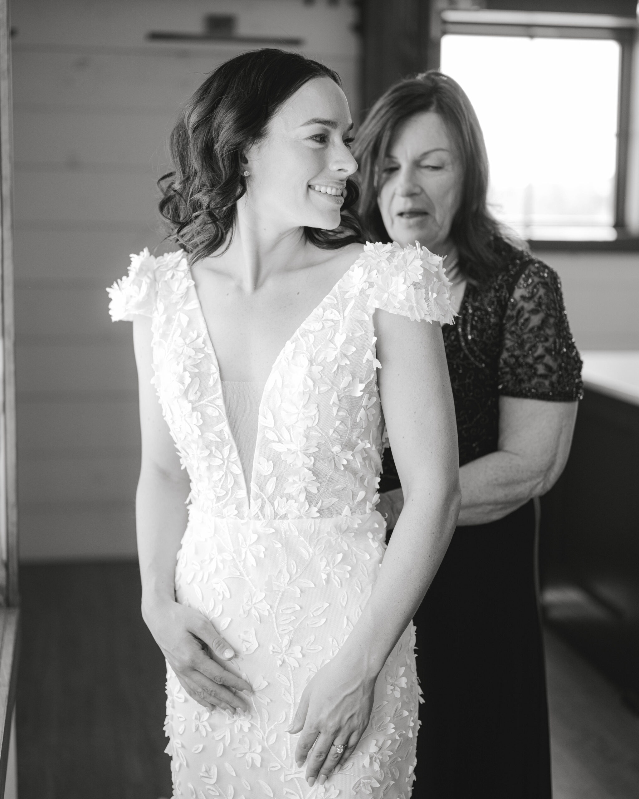 mother of the bride helping the bride into her dress