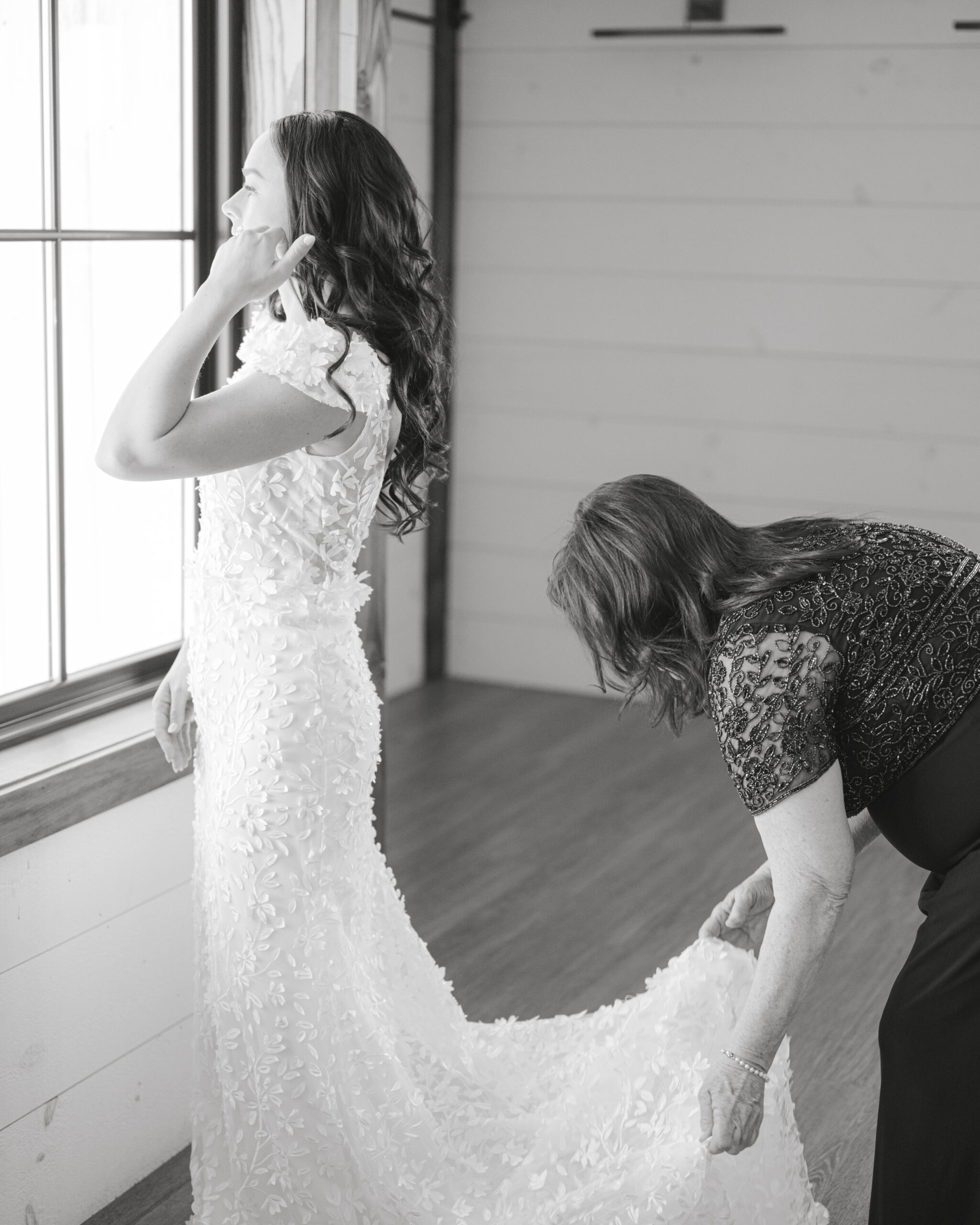 mother of the bride fixing bride's dress